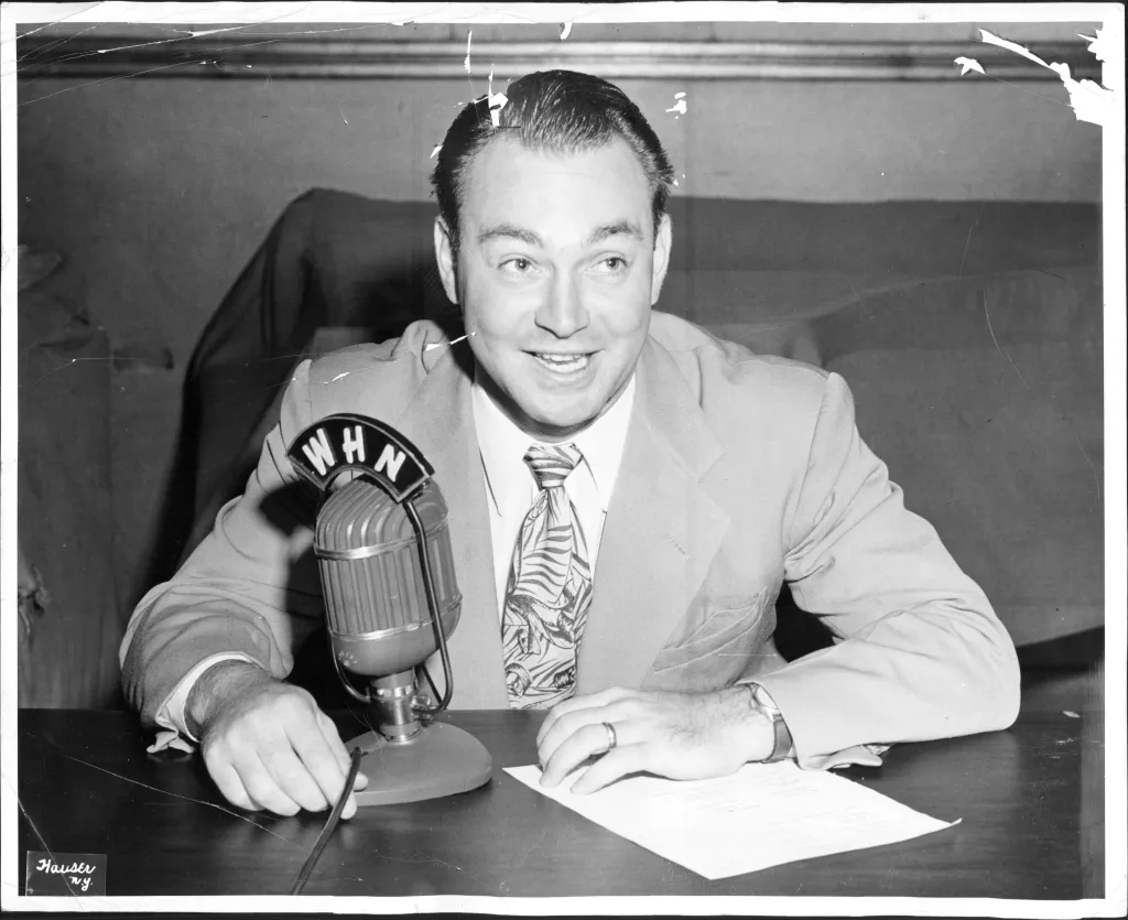 In this black and white photo, a young Marty Glickman speaks into a microphone.